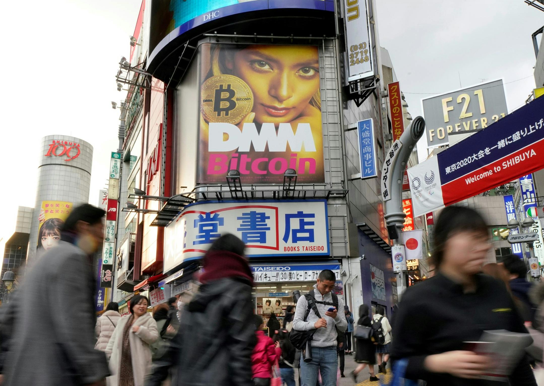 In this Feb. 11, 2018, photo, a huge advertisement of Bitcoin is displayed near Shibuya train station in Tokyo. The Japanese government is slapping penalties on several crypotocurrency exchanges in the country, after 58 billion yen ($530 million) of virtual coins were lost earlier this year from hacking. The Financial Services Agency, which has been checking the exchanges, said Thursday, March 8, 2018, that FSHO and Bit Station exchanges were ordered to halt operations for a month. (AP Photo/Shi