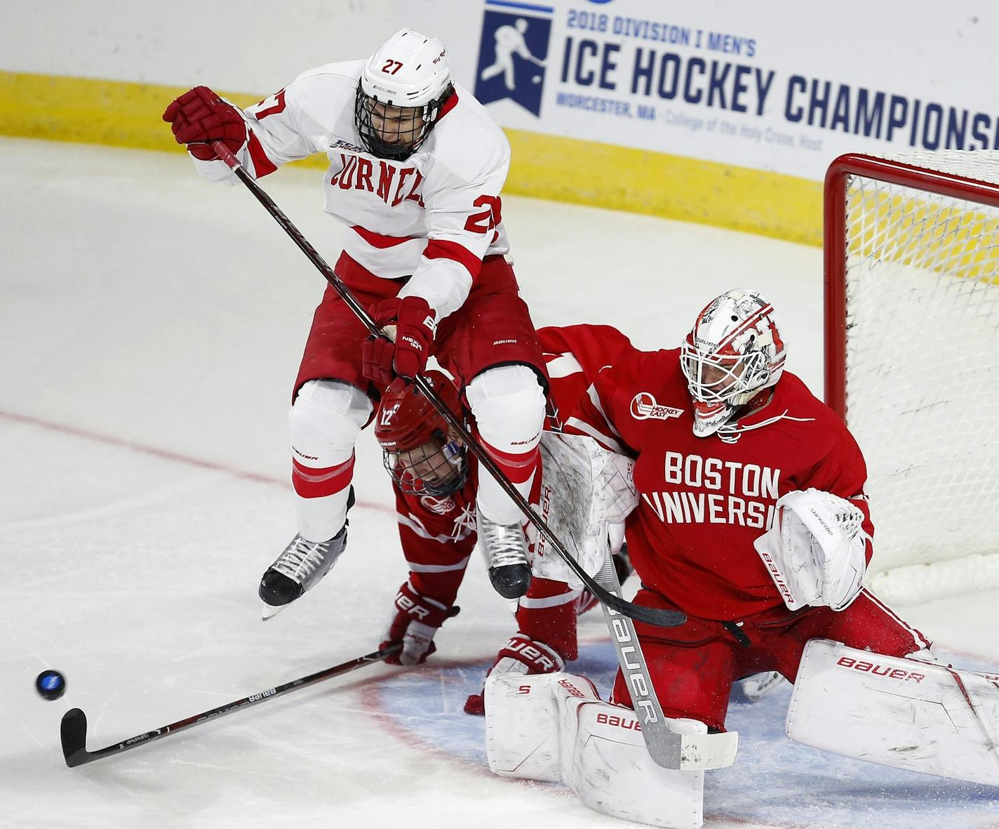 Cornell's Morgan Barron (27) screens the shot on Boston's Jake Oettinger, right, during the third period of an NCAA college hockey tournament regional game in Worcester, Mass., Saturday, March 24, 2018. Boston won 3-1. (AP Photo/Michael Dwyer)