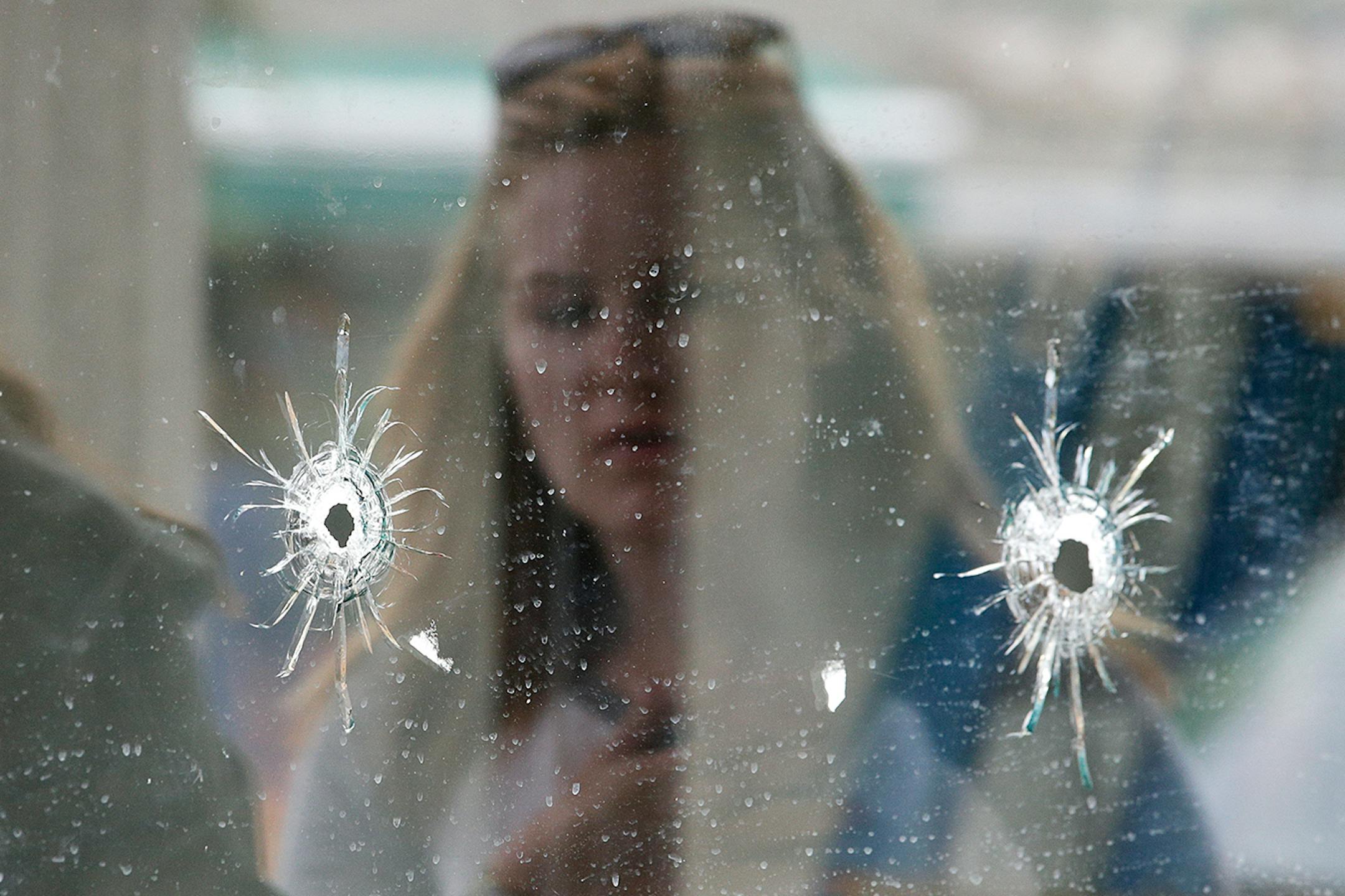 A woman looks at the bullet holes on the window of IV Deli Mark where Friday night's mass shooting took place by a drive-by shooter on Saturday, May 24, 2014, in Isla Vista, Calif. The shooter went on a rampage near a Santa Barbara university campus that left seven people dead, including the attacker, and seven others wounded, authorities said Saturday. Attorney Alan Shifman says the family of a man suspected in the shooting rampage called police several weeks ago after being alarmed by YouTube