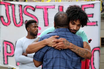 After giving an impassioned talk, Rev. Brian Herron, front, receives a hug from Jacob Ladda outside Gov. Mark Dayton's mansion as protestors gathered 