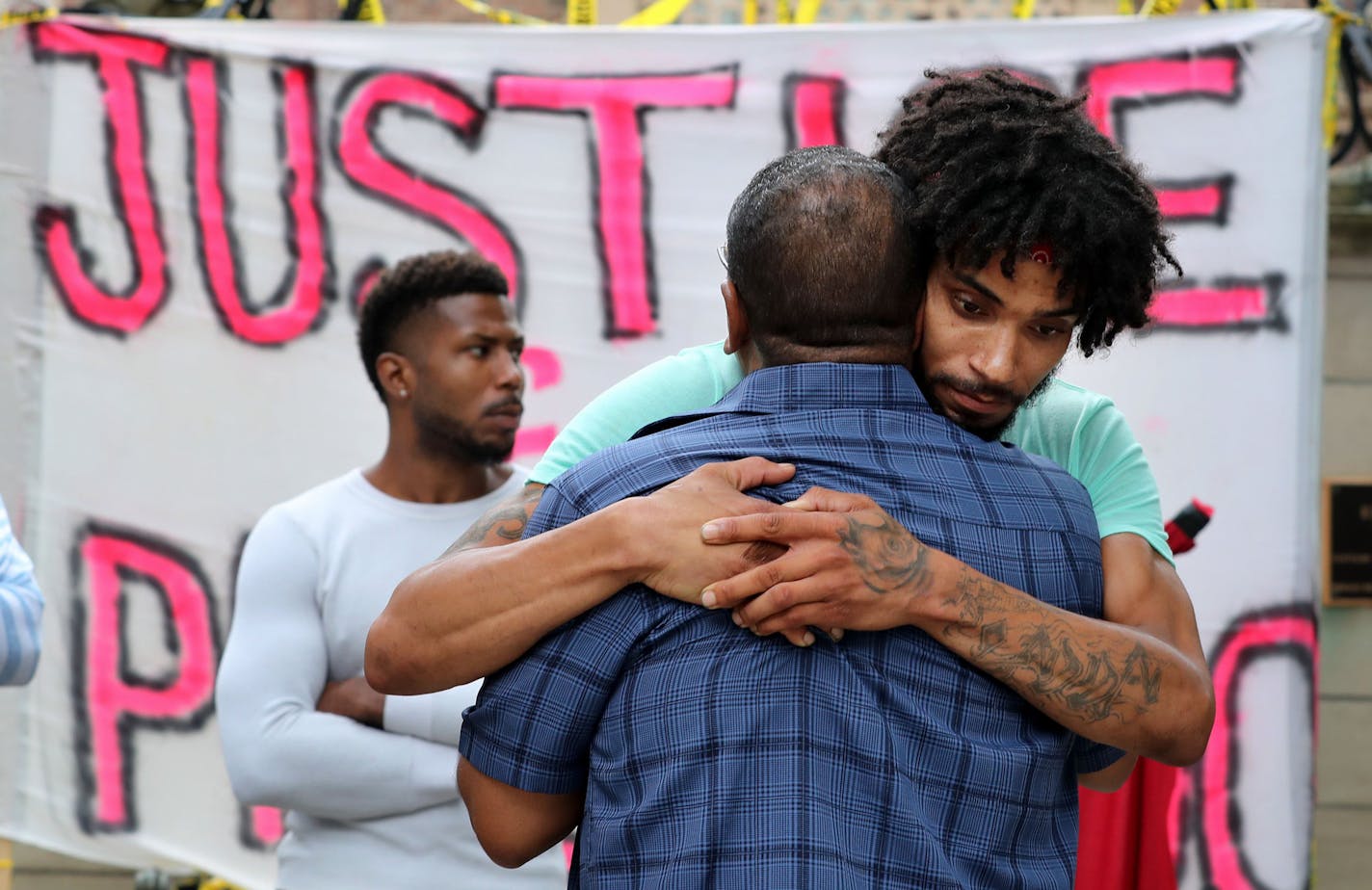 After giving an impassioned talk, Rev. Brian Herron, front, receives a hug from Jacob Ladda outside Gov. Mark Dayton's mansion as protestors gathered Thursday, July 7, 2016, in St. Paul