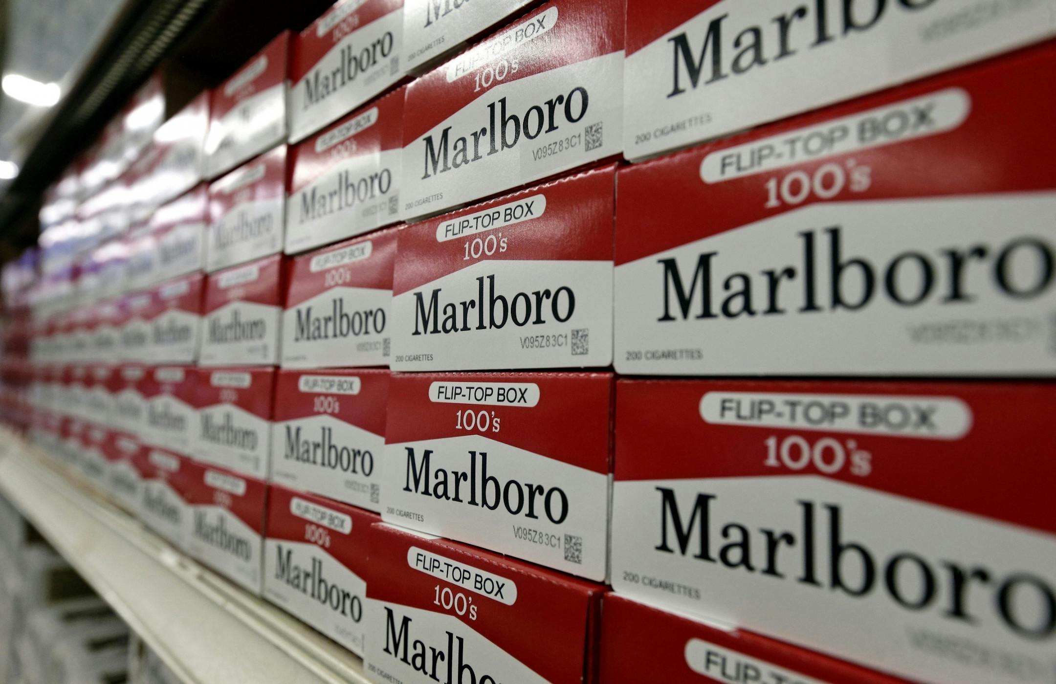 FILE- This June 14, 2018, file photo shows cartons of Marlboro cigarettes on the shelves at JR outlet in Burlington, N.C. Altria confirmed Tuesday, Aug. 27, 2019, that it is in talks to merge with Philip Morris International more than a decade after splitting itself into two companies. Altria has exclusively sold Marlboro and other cigarette brands in the U.S., while Philip Morris has handled international sales.
