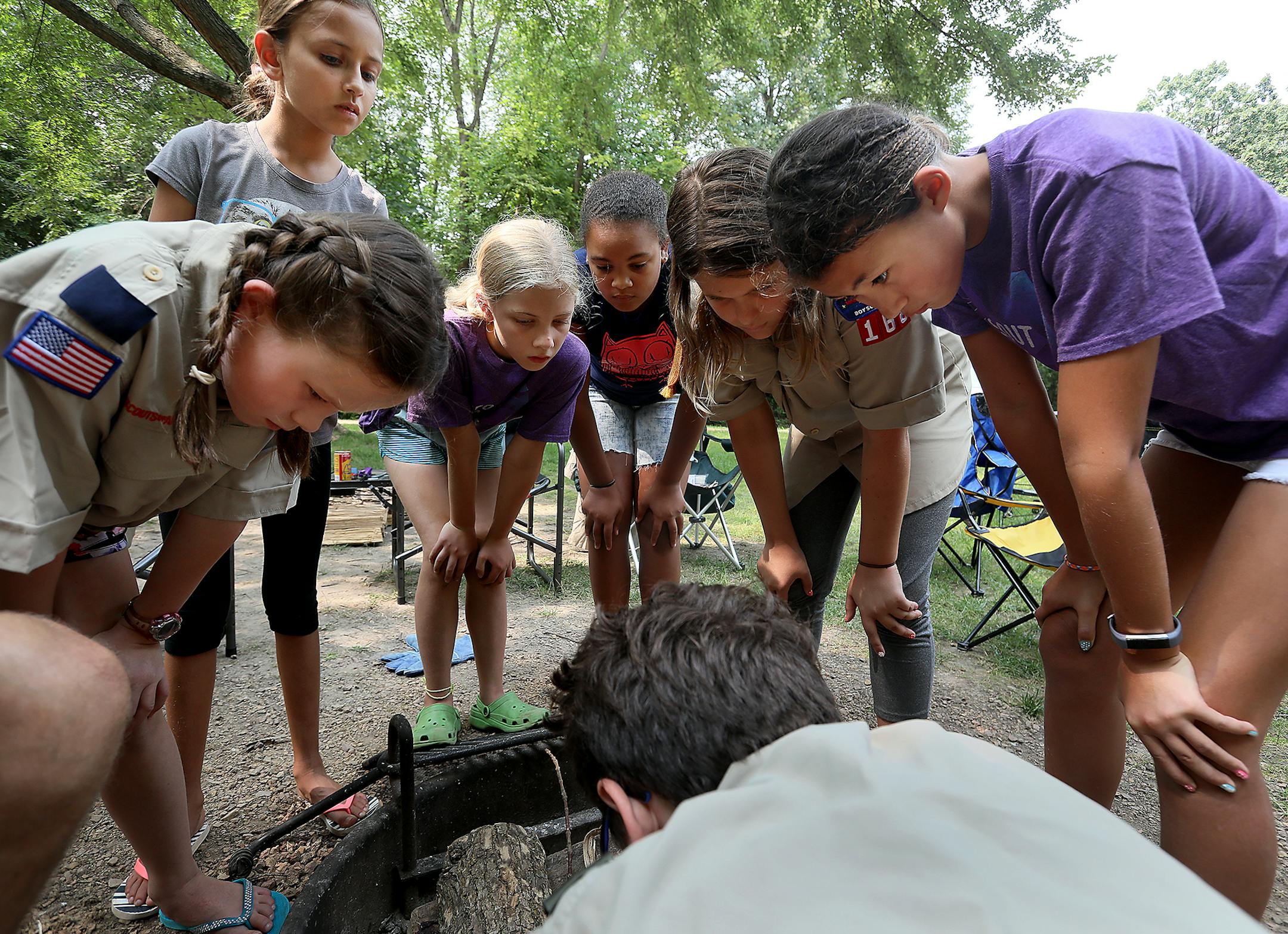 Members of Edina cub scout pack 168 are among the first girls in the country to be scouts - and they are holding their first campout, at Lake Auburn campground in Carver Park. Here, boy scout Miles Van Norman, lower center, shows the scouts how to build a fire in a fire ring at Carver Park Saturday, Aug. 18, 2018, in Victoria, MN. Looking on are scouts Marit Peterson, left to right, Charlotte Soundararajan, Iris Nordin, ZaZa Okundaye, Sylvia Van Norman and Sophia Hoffman.] DAVID JOLES ï dav
