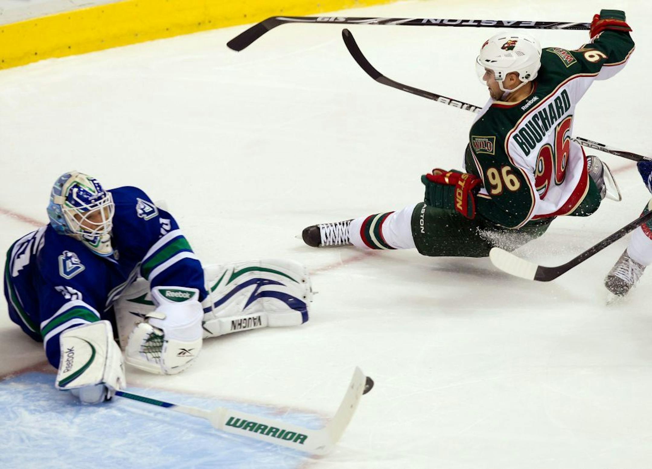 Vancouver Canucks' goalie Cory Schneider, left, makes the save as Minnesota Wild's Pierre-Marc Bouchard is tripped up by Canucks' Andrew Alberts, not pictured, during the second period of an NHL hockey game in Vancouver, British Columbia, Canada, on Saturday, Oct. 22, 2011.