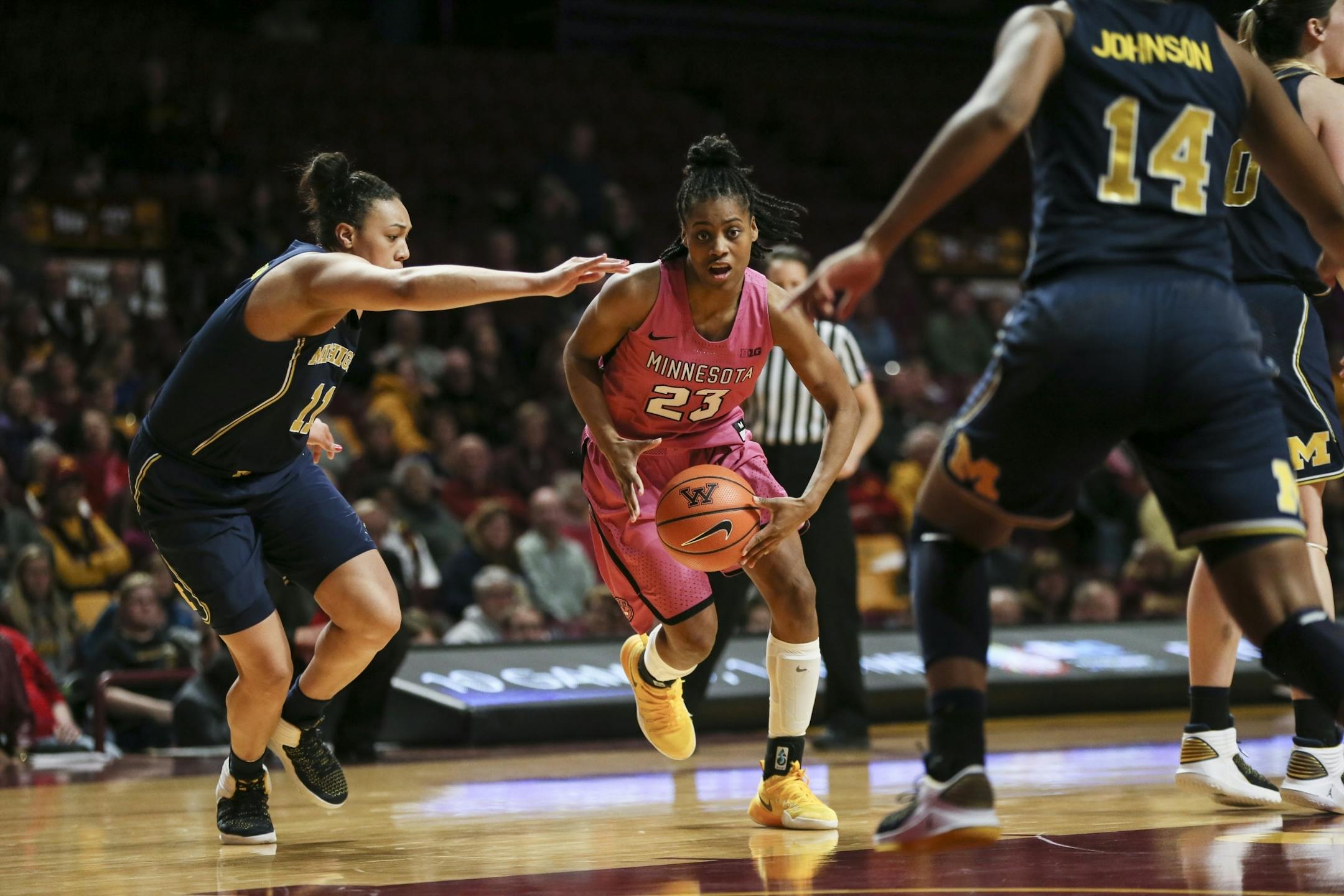 Minnesota Golden Gophers guard Kenisha Bell (23) pushed past Michigan players as she wound up for a shot in the second half.