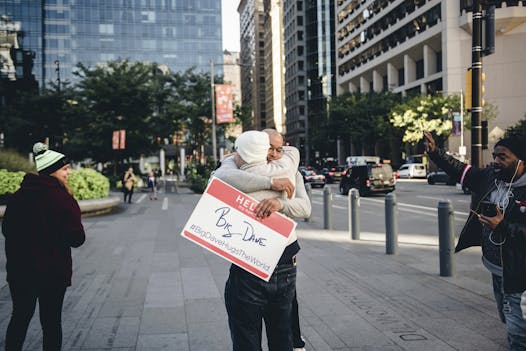 In this Oct. 19, 2018, photo, David “Big Dave” Sylvester hugs someone on a street in Philadelphia. Big Dave estimates around one-third of those passing by come in for a hug. Some leave in tears, as the small gesture proves its power in being able to elicit an emotional moment.