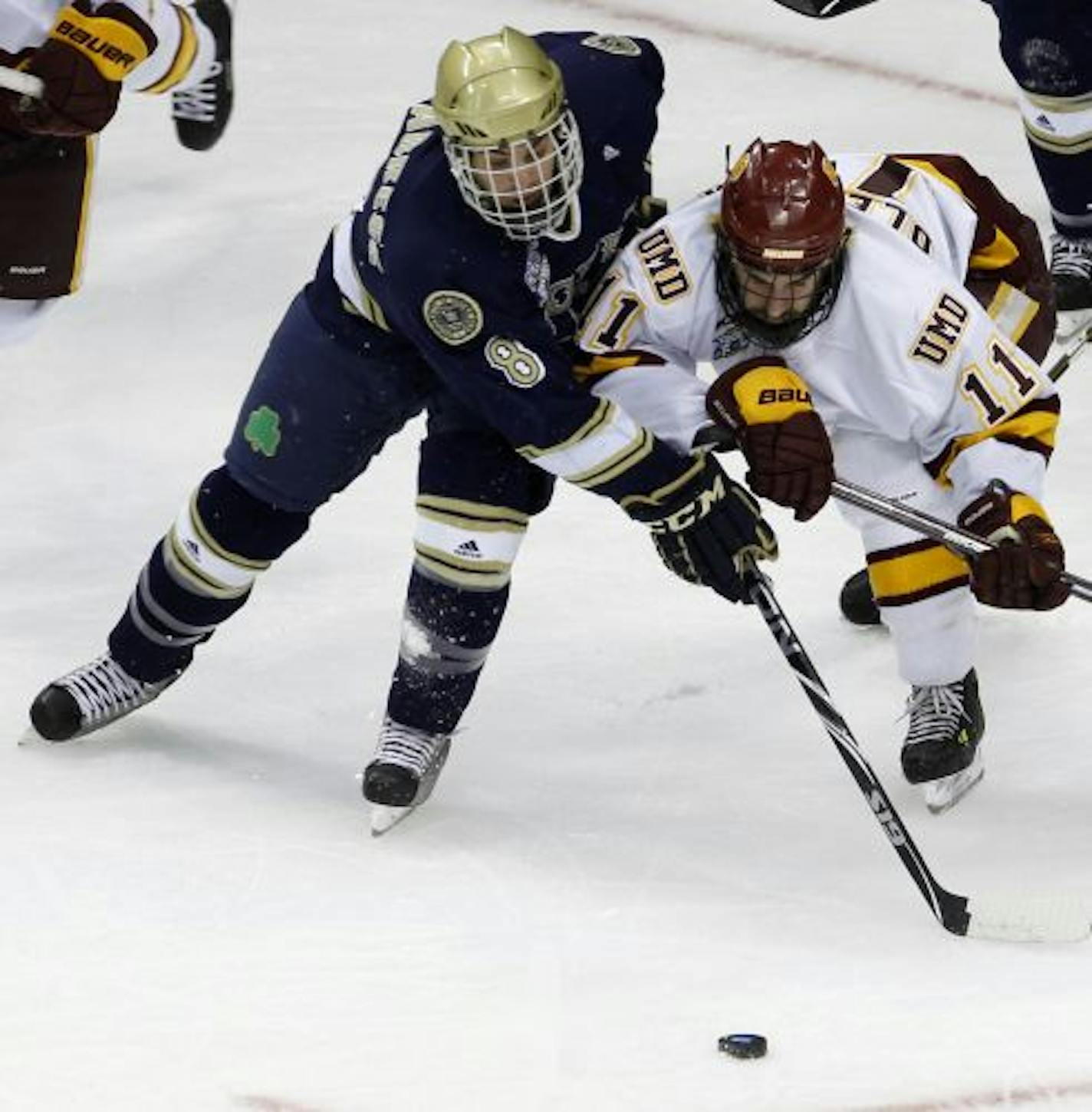 Notre Dame defenseman Sam Calabrese (8) and Minnesota Duluth center Travis Oleksuk (11) chase the puck during the first period of an NCAA Frozen Four college semifinal hockey game in St. Paul, Minn., Thursday, April 7, 2011.