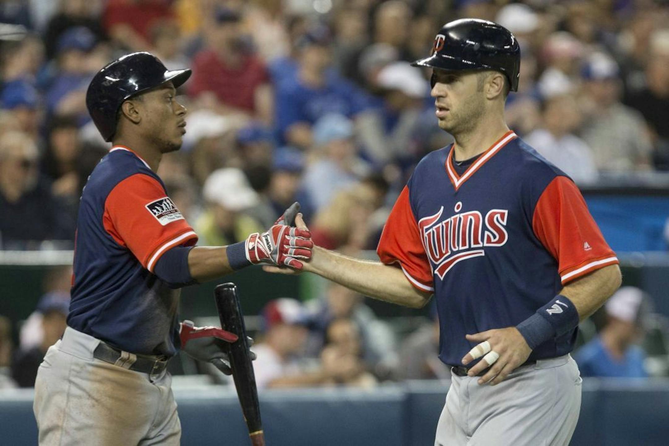 Minnesota Twins' Jorge Polanco, left, congratulates Joe Mauer, who scored on an Eduardo Escobar sacrifice fly against the Toronto Blue Jays during the fifth inning of a baseball game Friday, Aug. 25, 2017, in Toronto.