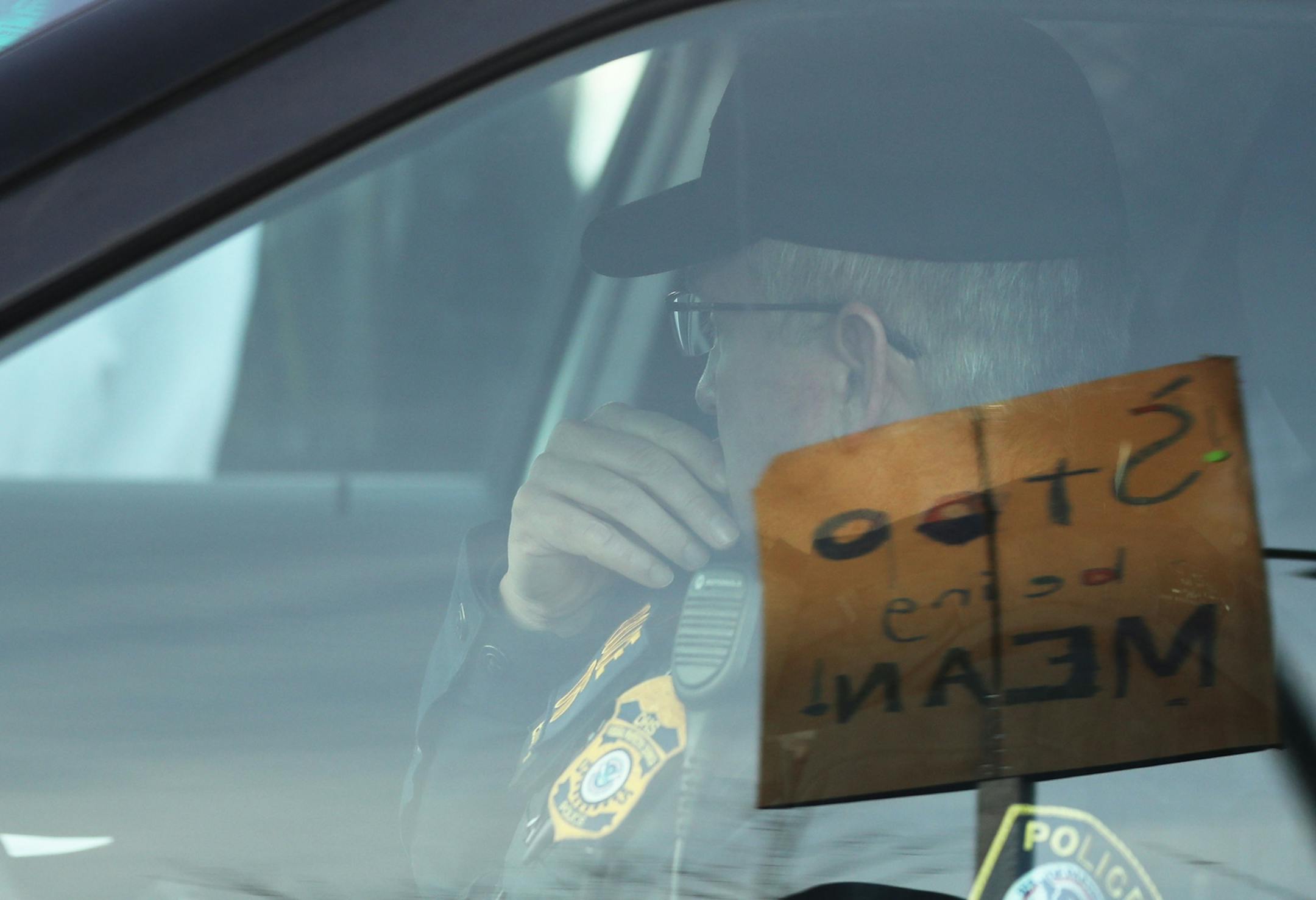 A Homeland Security police officer looks out from his vehicle at clergy members attempting to get inside the Whipple Federal Building to offer prayer and communion for detainees and their guards Tuesday, Oct. 29, 2019, in St. Paul, MN. Clergy and protestors gathered for a service and communion outside the Whipple Federal Building and to protest the naming of the building after the Episcopal bishop because deportations and other actions at the courthouse are in opposition to the beliefs of the Ep