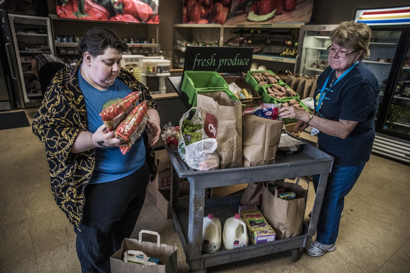 At 360 Communities Food Shelf in Burnsville, volunteer Kathy Marxer, right, helps Melissa Olsen pick up over 100 pounds of food items. Olsen says that good food shelves like this one are a rarity.