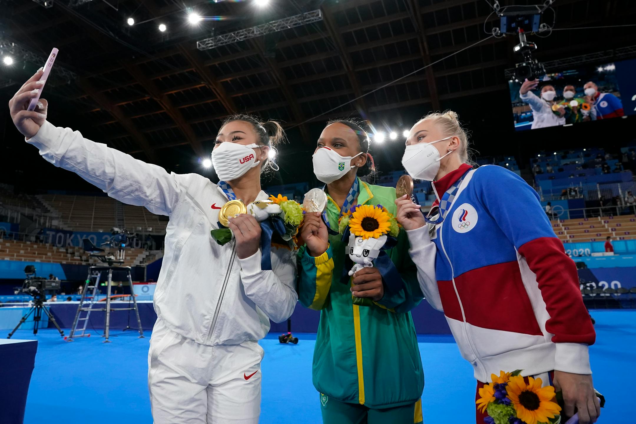 From left to right, Gold medalist Suni Lee of the Unites States, silver medalist Brazil's Rebeca Andrade, and bronze medalist Angelina Melnikova, of the Russian Olympic Committee, take a selfie after the medal ceremony for the artistic gymnastics women's all-around at the 2020 Summer Olympics, Thursday, July 29, 2021, in Tokyo. (AP Photo/Gregory Bull)