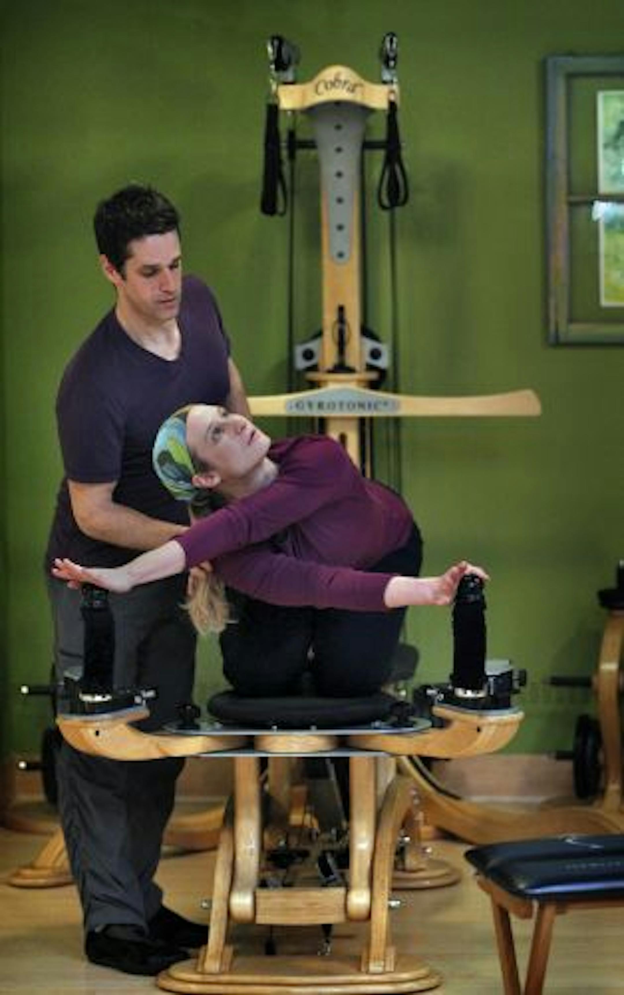 Christian Twigg works with Natalie Brown on the Gyrotronics equipment at 'The Awaken Pilates studio in the Lyn-lake neighborhood.