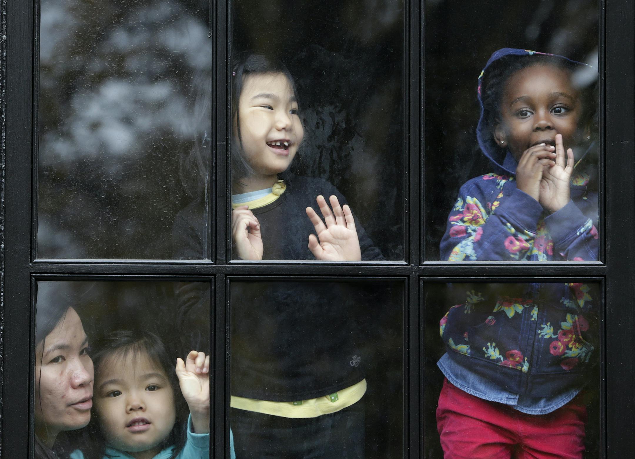 Children look out a window while trying to get a glimpse of balloons during the Macy's Thanksgiving Day Parade, Thursday, Nov. 27, 2014, in New York. (AP Photo/Julio Cortez)