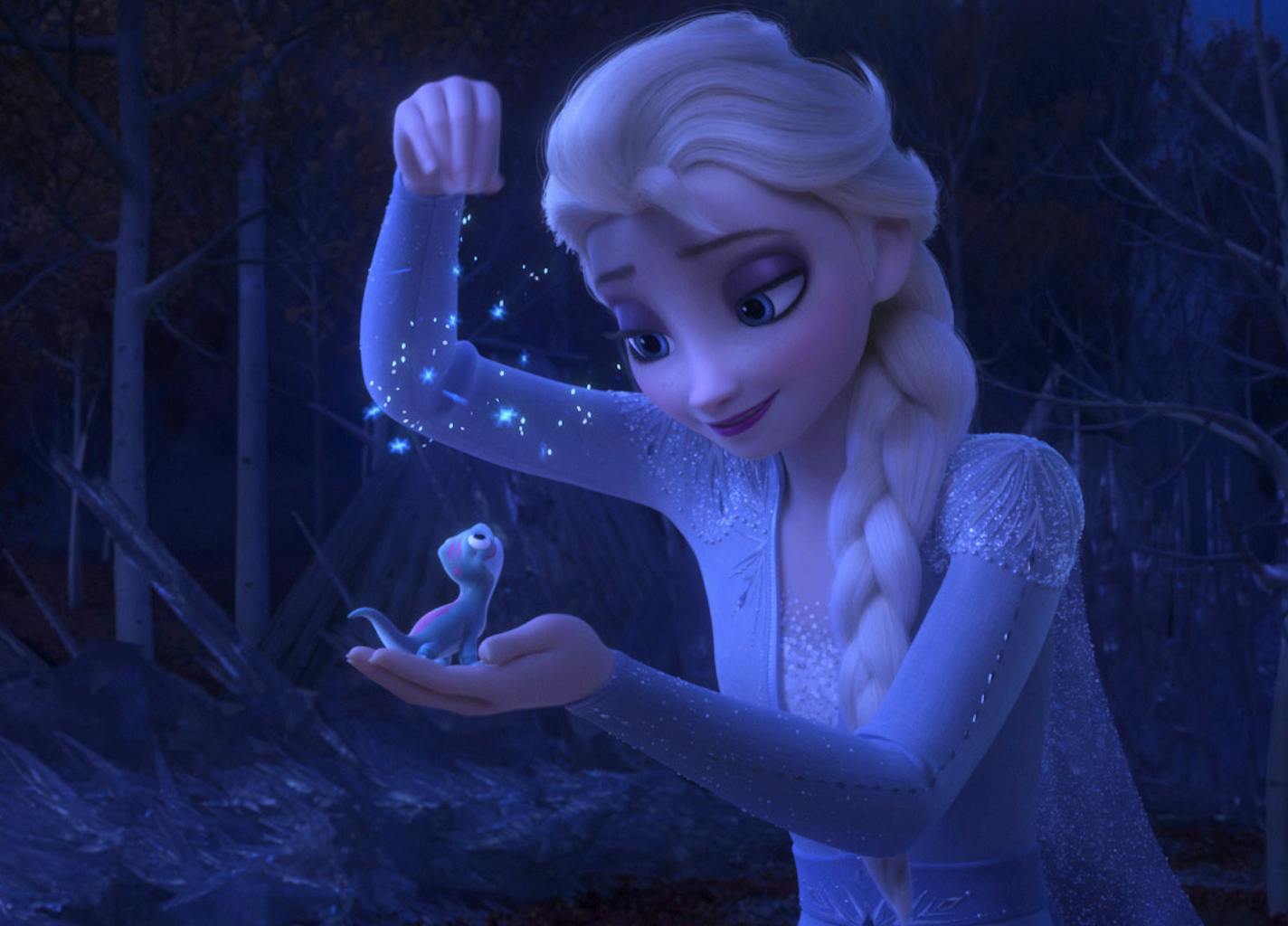 This image released by Disney shows Elsa, voiced by Idina Menzel, sprinkling snowflakes on a salamander named Bruni in a scene from the animated film, "Frozen 2." (Disney via AP)