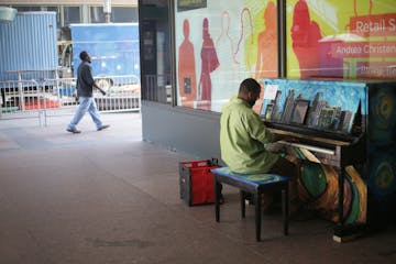 Walter Hampton of St. Paul plays a piano outside of the IDS Center on Wednesday, June 8, 2016. The piano, painted by artist Sam Basques, is one of 25 