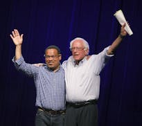 Minnesota Rep. Keith Ellison, left, waves to the audience with Sen. Bernie Sanders, right, at a rally to give support for his attorney general bid at 