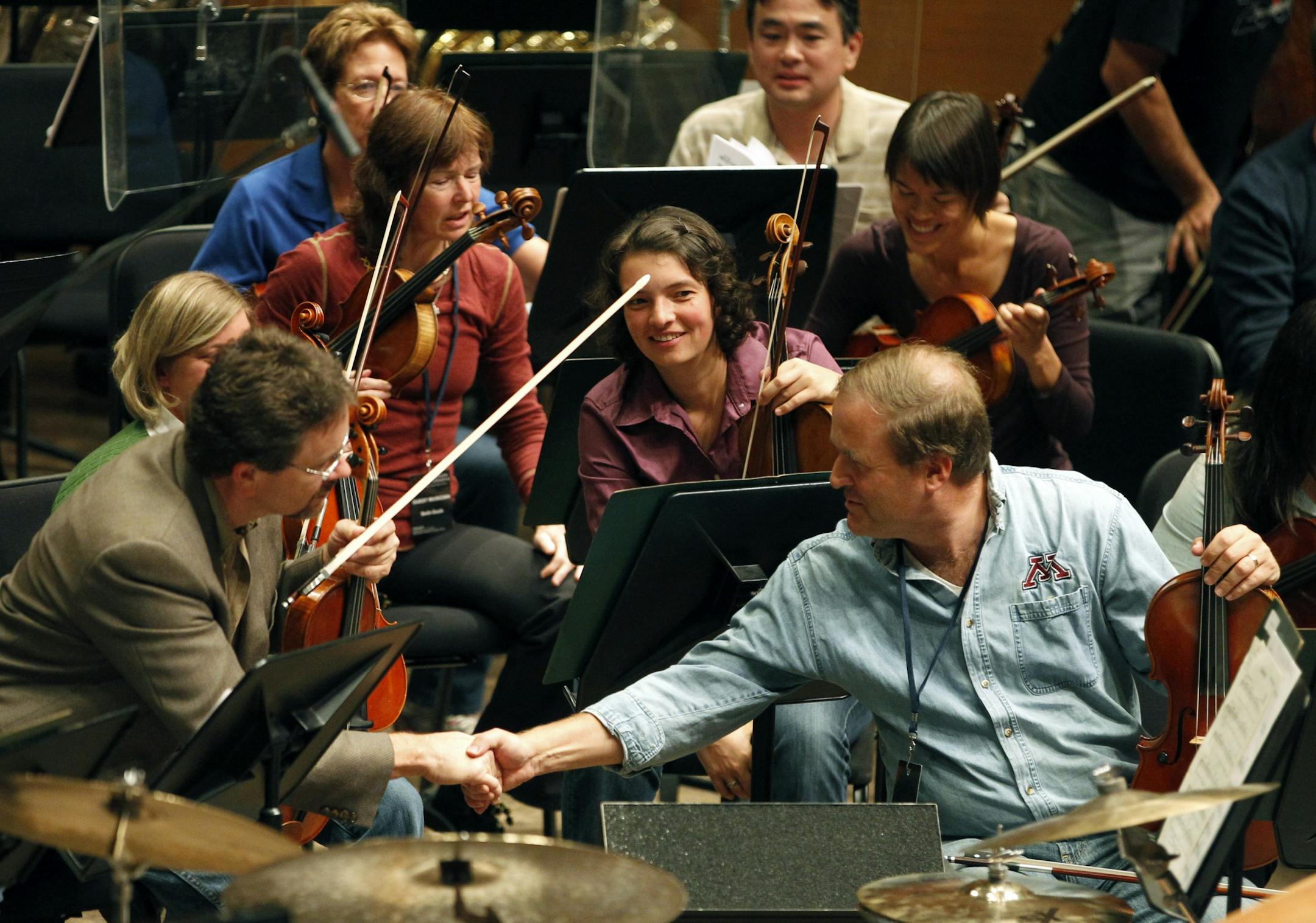 The orchestra's Mike Adams, left, shook Chuck Clay's hand at rehearsal during the orchestra fantasy camp. Amateur musicians are getting a chance to rehearse and perform alongside the Minnesota Orchestra professionals.