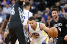 Golden State's Stephen Curry, center, works around the Timberwolves' Nemanja Bjelica, left, during the first half Friday night.