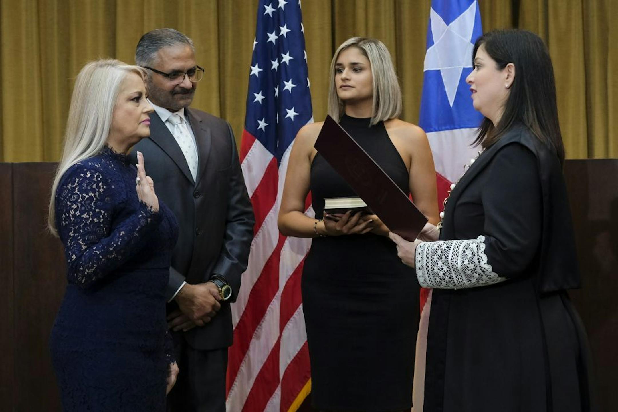 Justice Secretary Wanda Vazquez is sworn in as governor of Puerto Rico by Supreme Court Justice Maite Oronoz, in San Juan, Puerto Rico, Wednesday, Aug. 7, 2019. Vazquez took the oath of office early Wednesday evening at the Puerto Rican Supreme Court, which earlier in the day ruled that Pedro Pierluisi's swearing in last week was unconstitutional. Vazquez was joined by her daughter Beatriz Diaz Vazquez and her husband Judge Jorge Diaz.