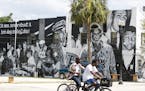 People bike past a mural on the Eastside Brotherhood Club building that depicts "Ax Handle Saturday" on Thursday, June 18, 2020 in Jacksonville. The R
