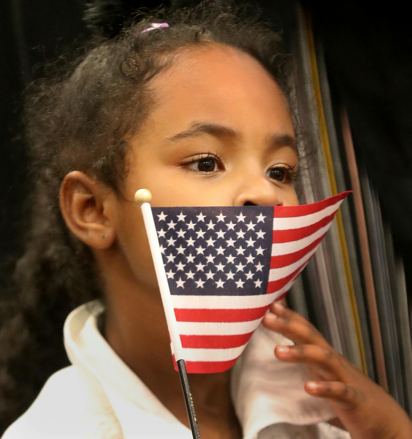 Muna Ibrahim, 4, shyly held an American flag while standing next to her mother, Hadil Hassan of Maplewood, after Hassan became a U.S. citizen at the May 24 naturalization ceremony at the Roseville Skating Center.