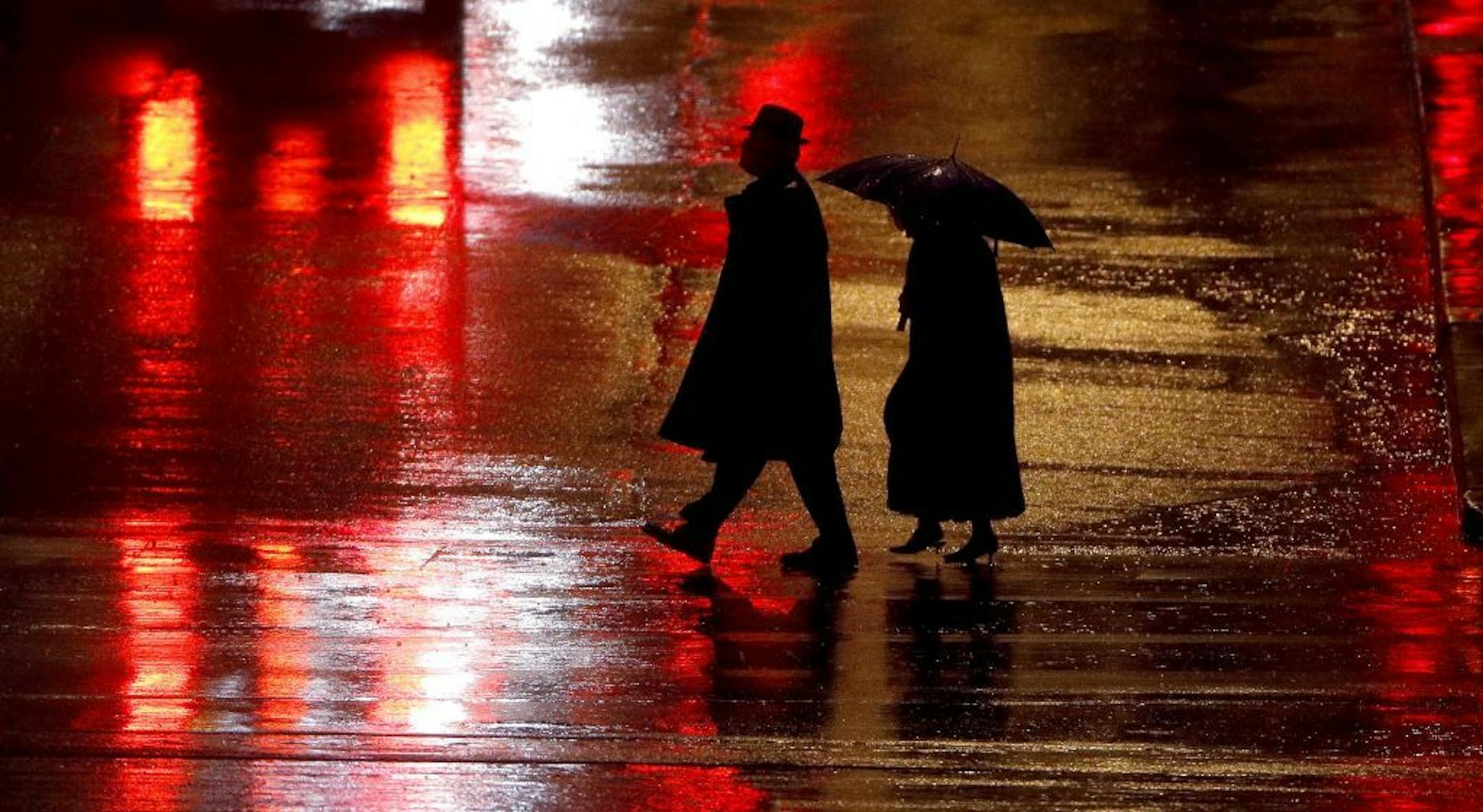 Pedestrians are silhouetted against wet pavement in Kansas City, Mo. Several factors have contributed to the increase in pedestrian deaths, including motorists who are speeding, distracted or drowsy and more people are walking after dark.