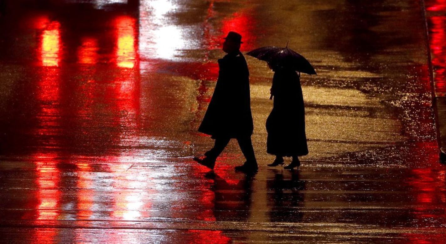 Pedestrians are silhouetted against wet pavement in Kansas City, Mo. Several factors have contributed to the increase in pedestrian deaths, including motorists who are speeding, distracted or drowsy and more people are walking after dark.