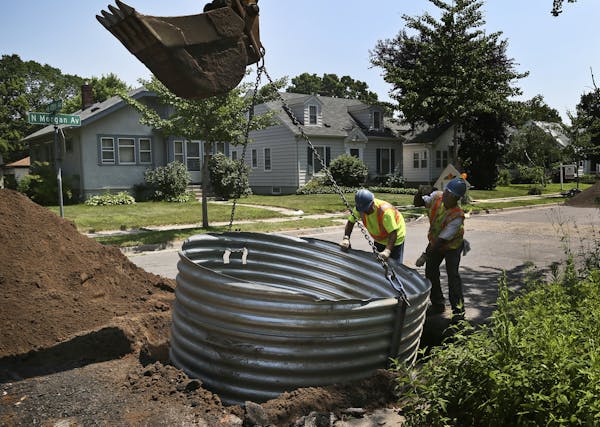 City water worker Ernest Odom, right, helps direct a backhoe operator on where to place a galvanized shoring box to prevent a cave-in on a water main 