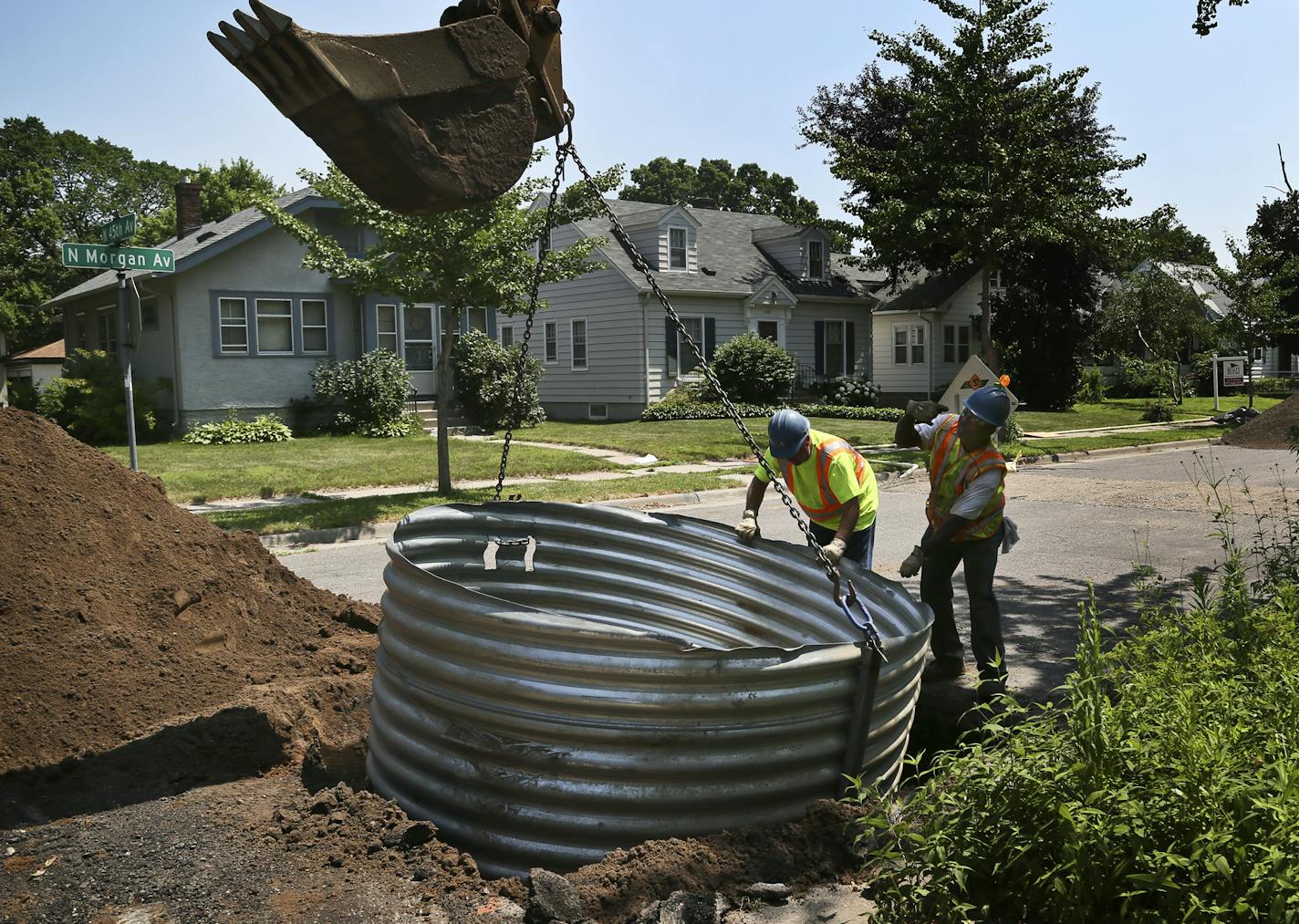 City water worker Ernest Odom, right, helps direct a backhoe operator on where to place a galvanized shoring box to prevent a cave-in on a water main cleaning and lining project at Morgan Avenue N. at 45th Wednesday, July 10, 2013, in Minneapolis, MN.](DAVID JOLES/STARTRIBUNE) djoles@startribune.com Recent water main breaks in the city of Minneapolis reveal an aging infrastructure with some water pipes made of cast iron and having never been cleaned or maintained in the 100 plus years the pipes