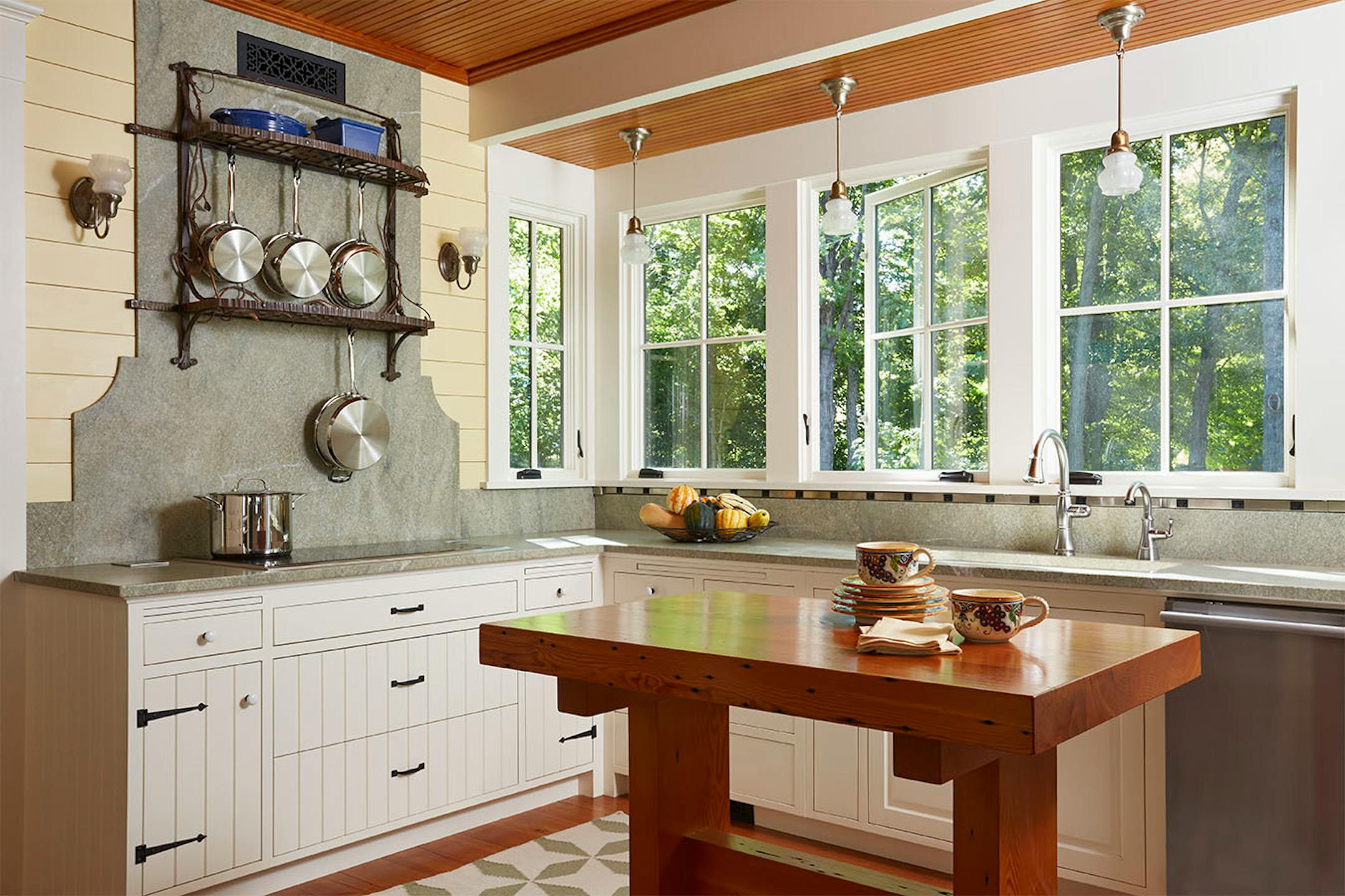 The kitchen combines shiplap boards, granite surfaces and a reclaimed wood work table.