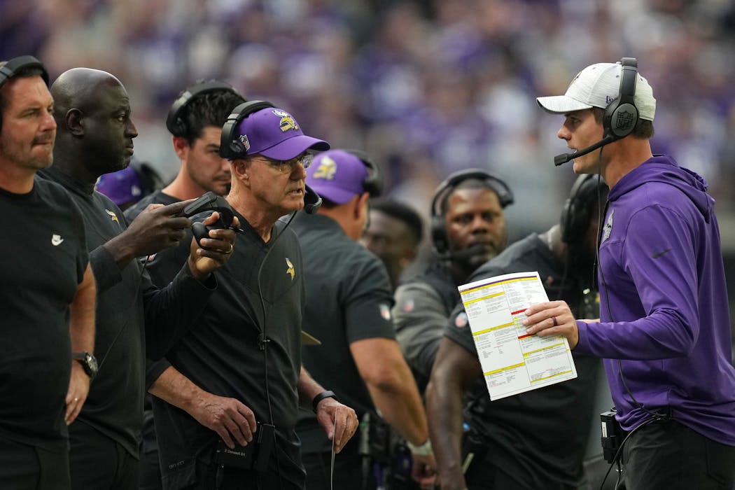 Vikings head coach Kevin O’Connell, right, talks to defensive coordinator Ed Donatell (left, in the purple hat) and other assistants during the team’s season opener against the Packers.