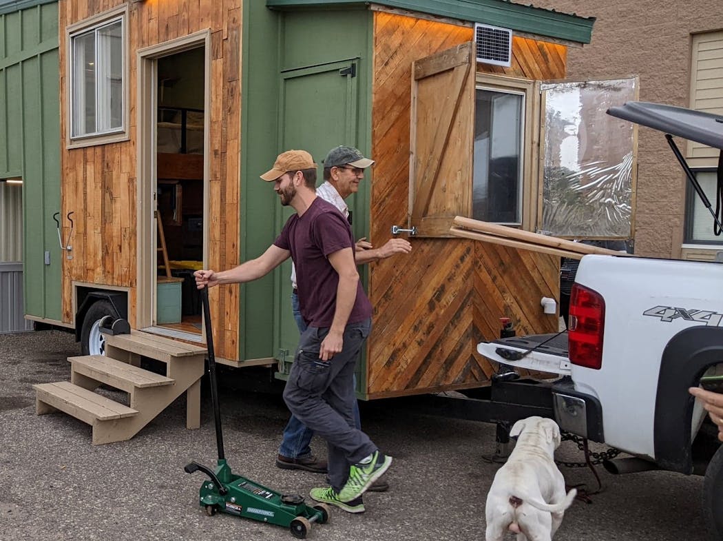 James MacKenzie, an electrician from Columbia Heights, helps unload the tiny home that he built for the homeless.