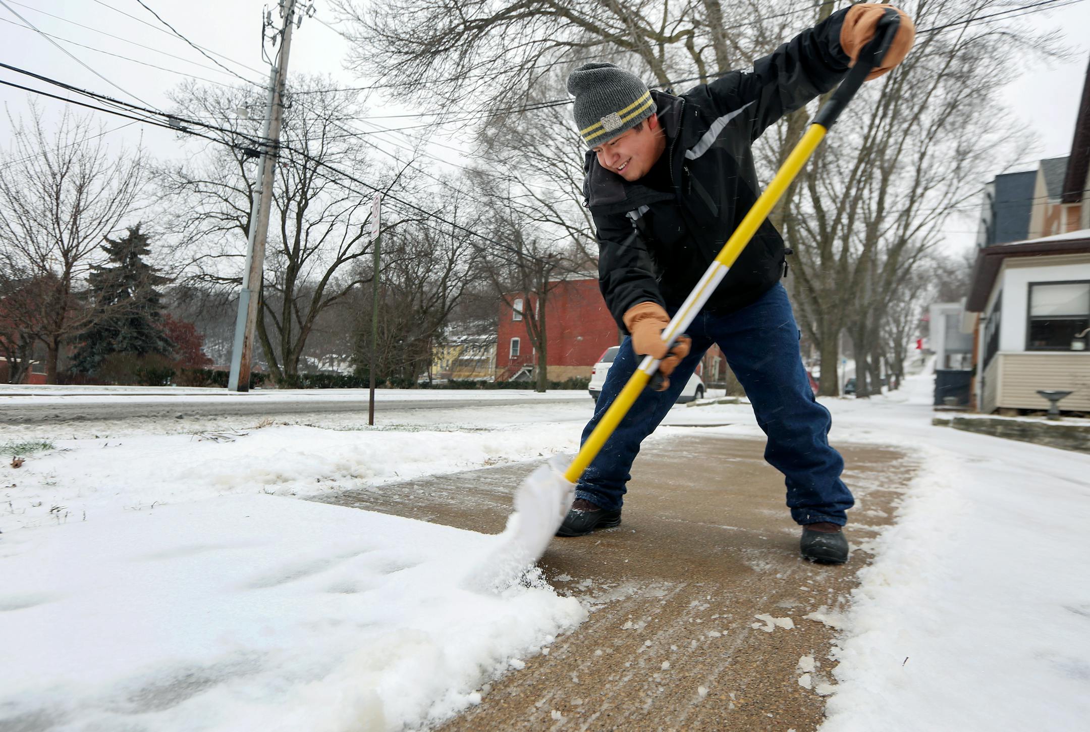 Isidro Jimenez Arguelles, of Dubuque, Iowa, removes snow along 3rd Street in Dubuque as a winter storm hit the area on Monday, Dec. 28, 2015.