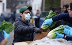 A man wore a mask as he was given a head of lettuce during the free grocery giveaway event Wednesday at the Minneapolis Police Activities League. ] AN