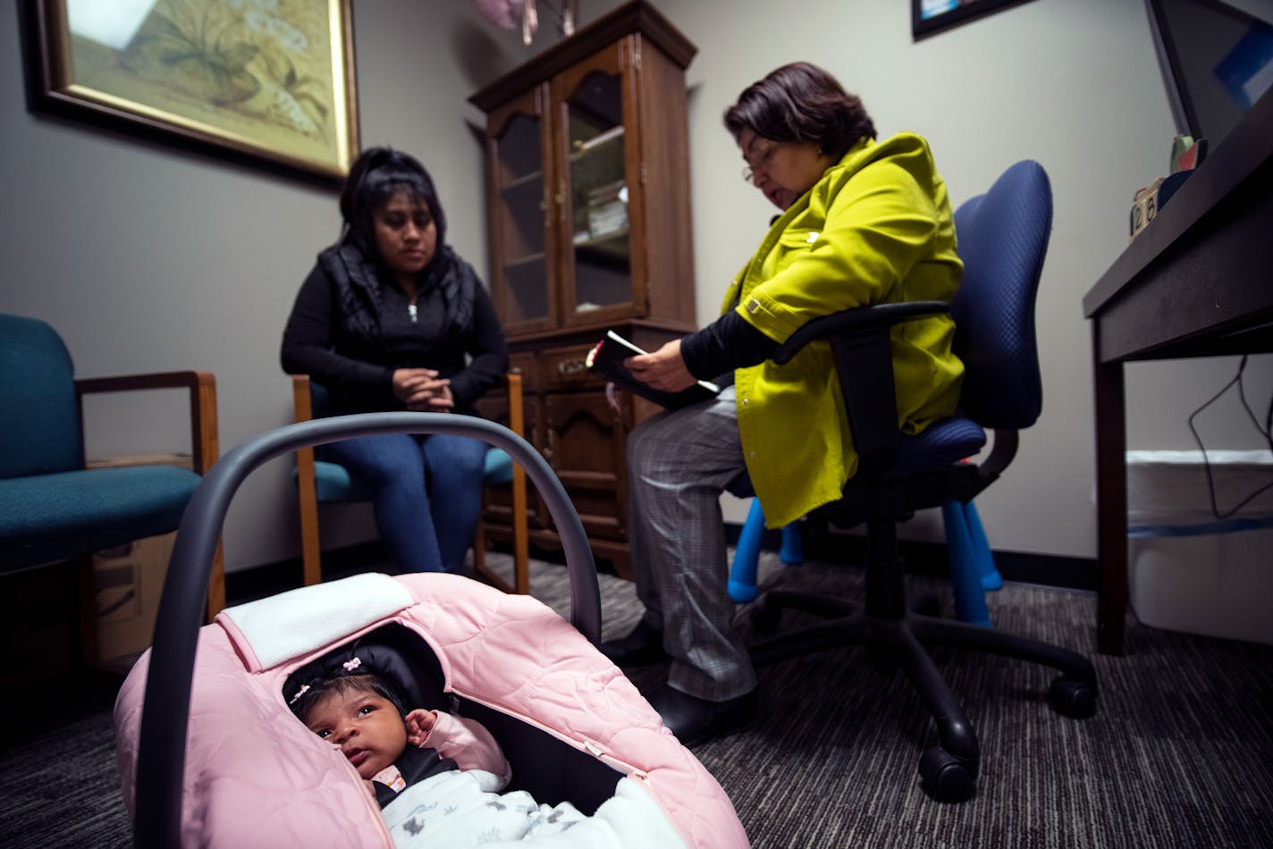 Sara Hernandez, right, reads a bible verse to Geholmin and her one month old baby Ariadnee as they arrive for a weekly visit to Helping Hand Pregnancy Center in Worthington, Minn., on Tuesday, Feb. 28, 2023. ] RENEE JONES SCHNEIDER • renee.jones@startribune.com