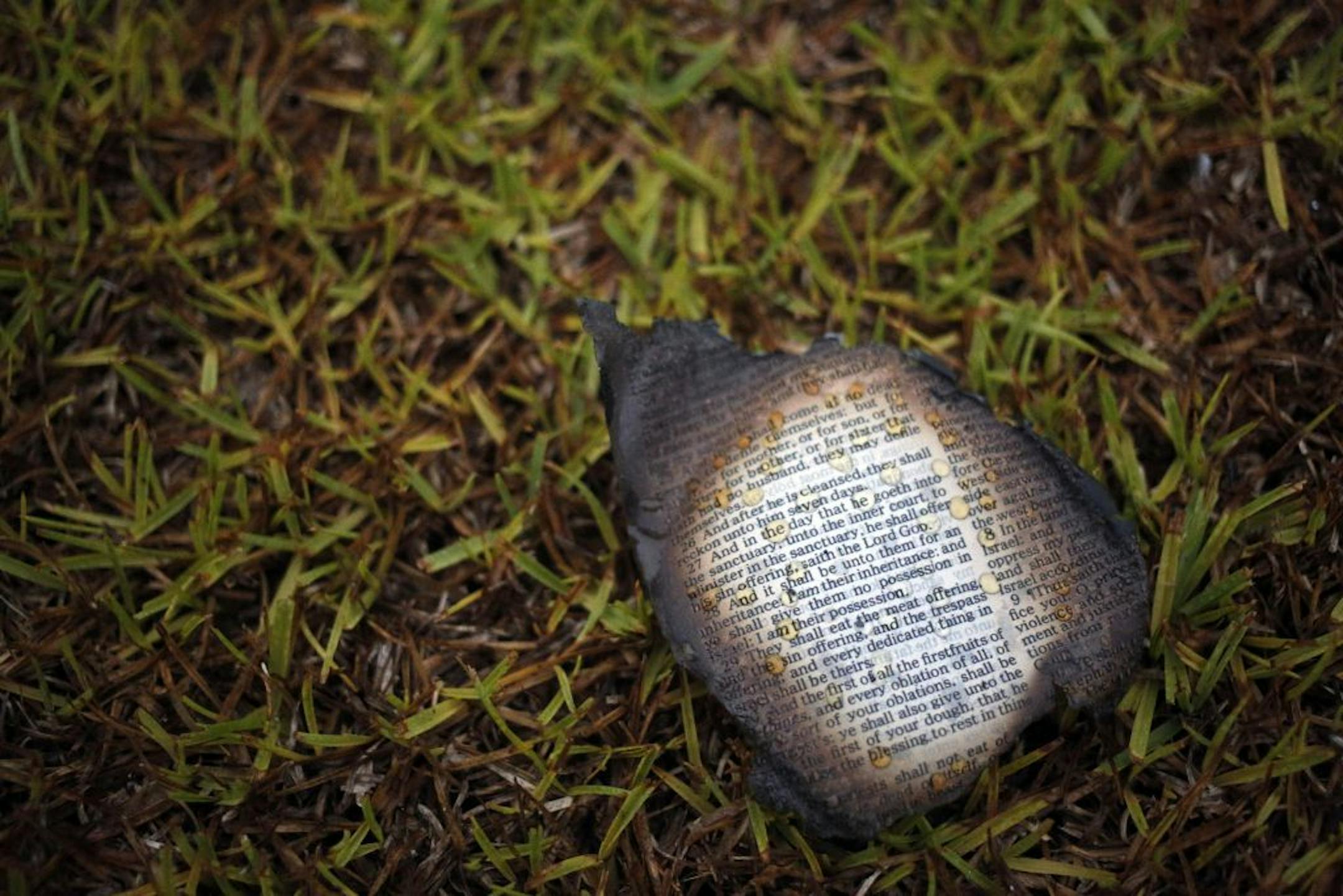 A charred bible page is seen outside Mount Zion African Methodist Episcopal church, Wednesday, July 1, 2015, in Greeleyville, S.C. The African-American church, which was burned down by the Ku Klux Klan in 1995, caught fire Tuesday night, but authorities said arson is not the cause.
