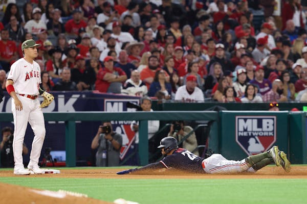 Byron Buxton slides safely into third base off of a single by Kyle Farmer as Los Angeles Angels third baseman Gio Urshela looks on during Saturday’s