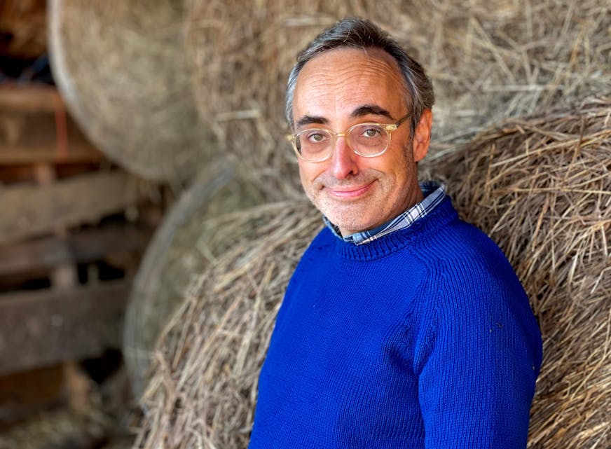 photo of author Gary Shteyngart, in a bright blue sweater in front of bales of hay