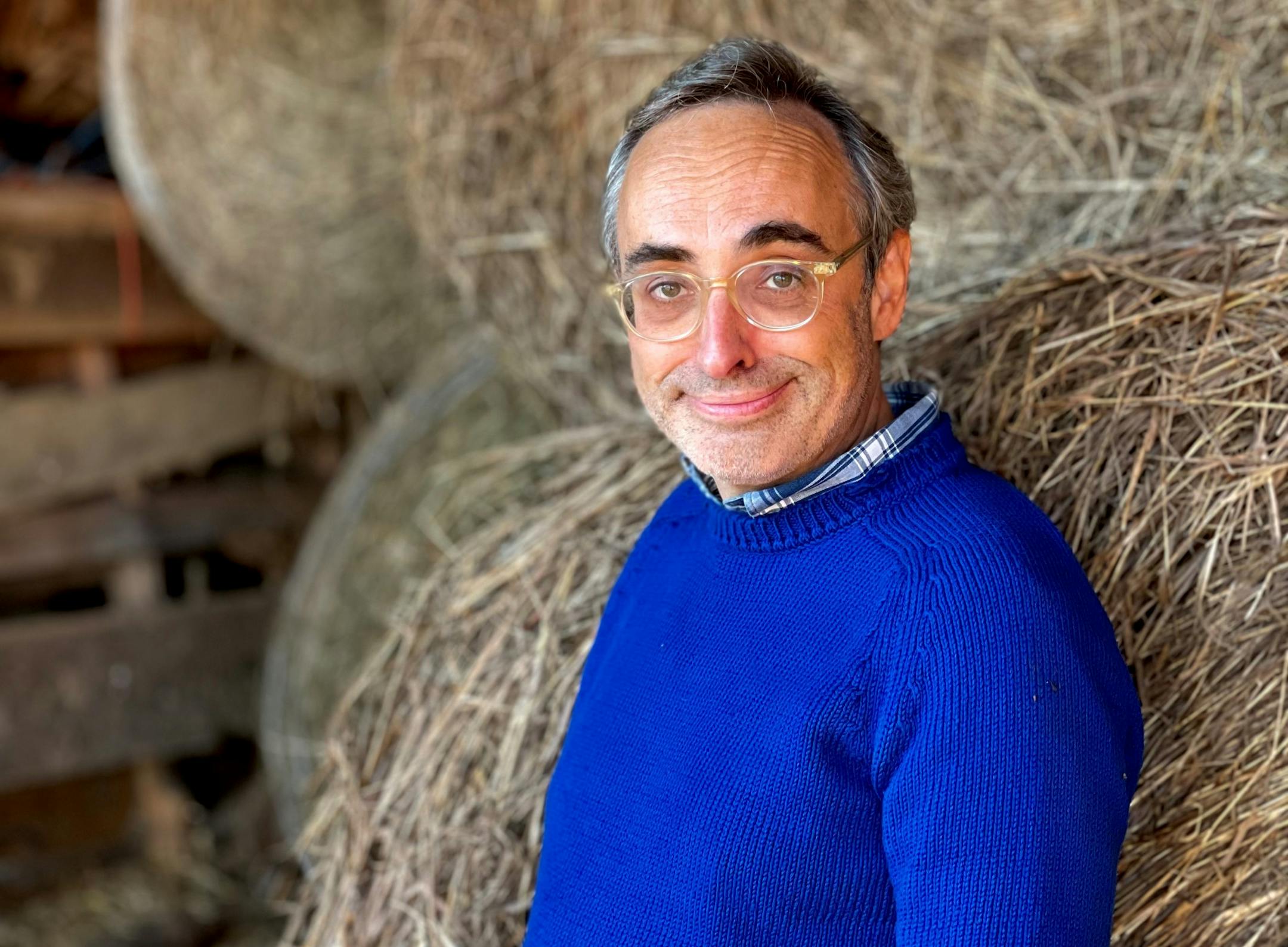 photo of author Gary Shteyngart, in a bright blue sweater in front of bales of hay