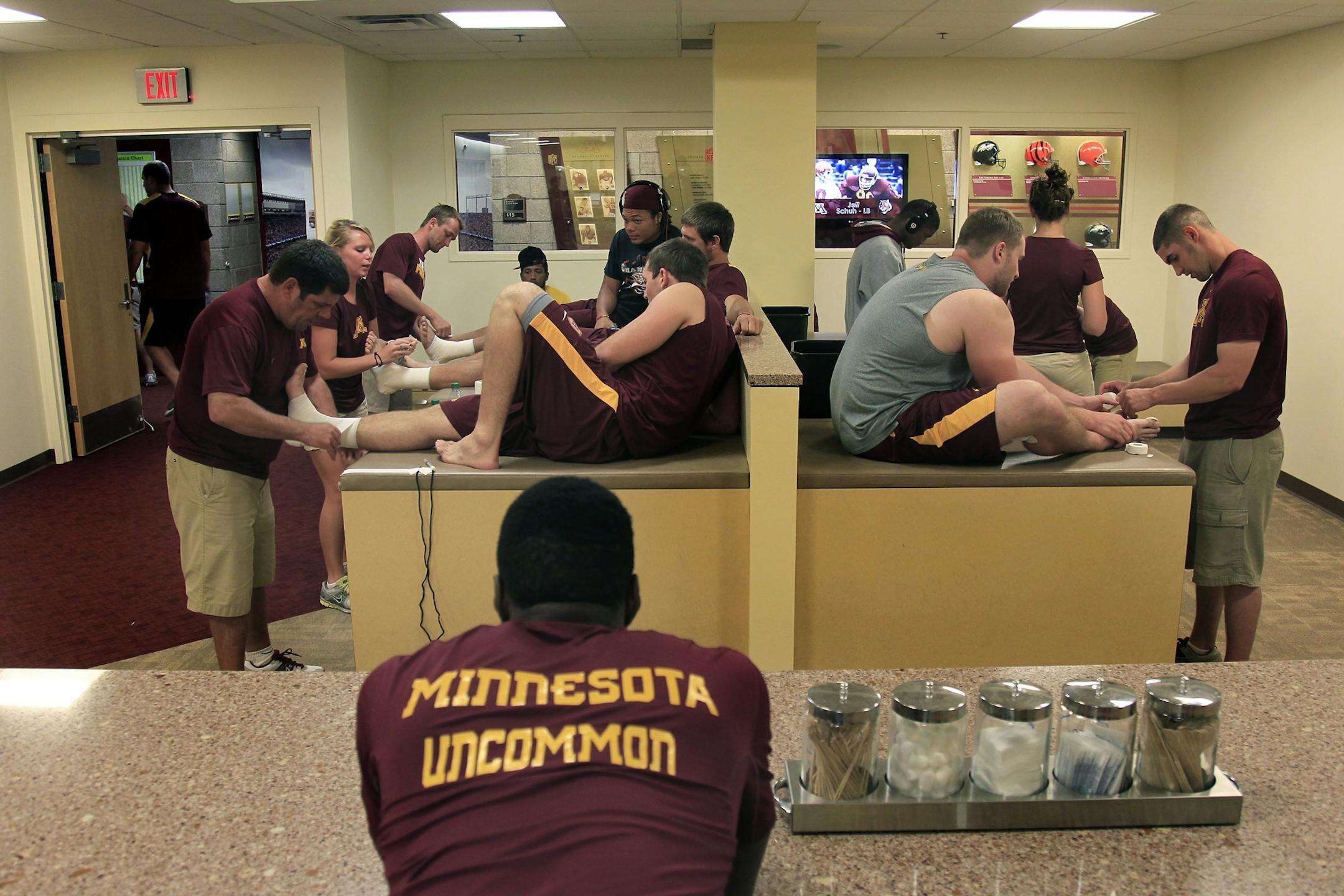 Minnesota Gophers trainers, led by Ed Lochrie, left, taped a table full of players before the afternoon practice at the Bierman football complex, Thursday, August 9, 2012. (ELIZABETH FLORES/STAR TRIBUNE) ELIZABETH FLORES � eflores@startribune.com