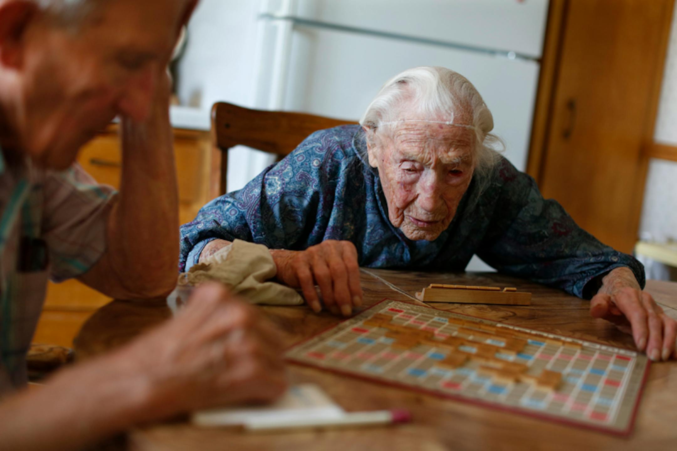 At her home in Pottsdam, Anna Stoehr plays Scrabble with her son Harlan, 83 who is changing the hoses on her washer. She is perhaps the oldest person who lives alone. She does not have a special diet but likes to bakes her own bread. She also likes to eat liverwurst, butter, and bacon.