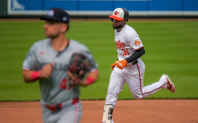 The Orioles' Cedric Mullins rounds the bases after hitting a two-run, walk-off home run while Twins second baseman Edouard Julien jogs off the field W