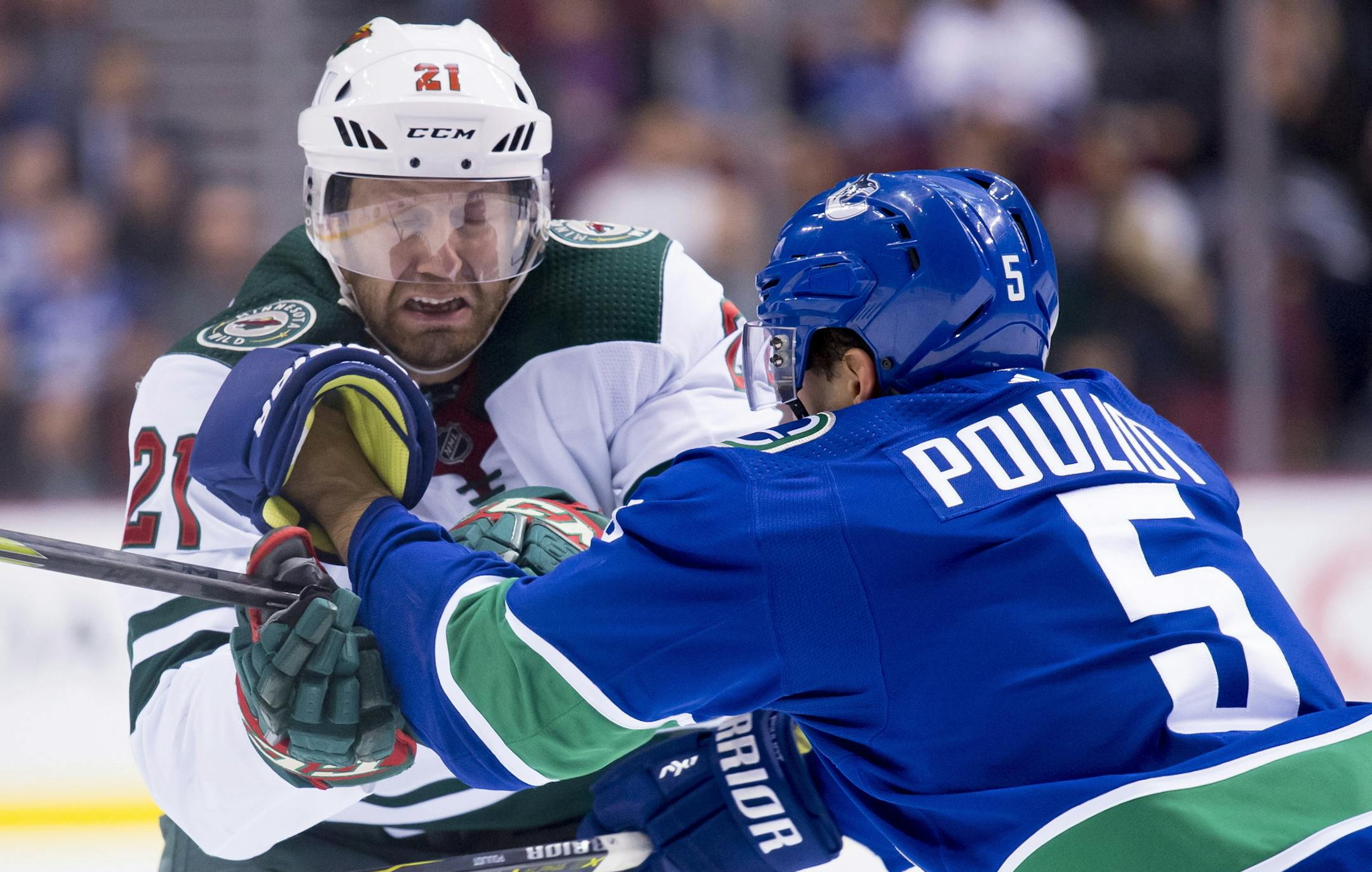 Minnesota Wild centre Eric Fehr (21) fights for control of the puck with Vancouver Canucks defenseman Derrick Pouliot (5) during first period NHL hockey action in Vancouver, British Columbia, Monday, Oct. 29, 2018. (Jonathan Hayward/The Canadian Press via AP)