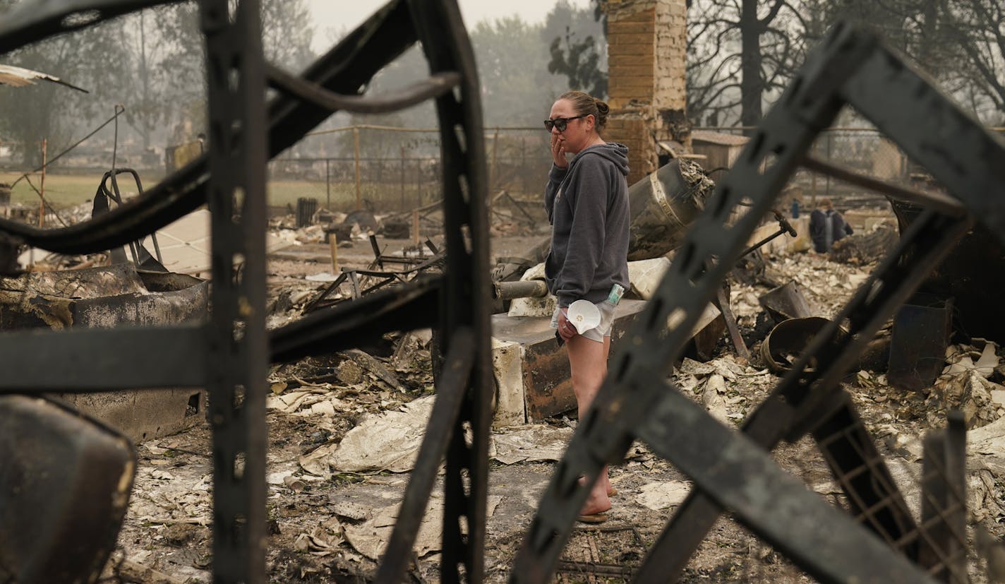 Desiree Pierce reacts as she visits her home destroyed by the Almeda Fire, Friday, Sept. 11, 2020, in Talent, Ore. "I just needed to see it, to get some closure," said Pierce. (AP Photo/John Locher)