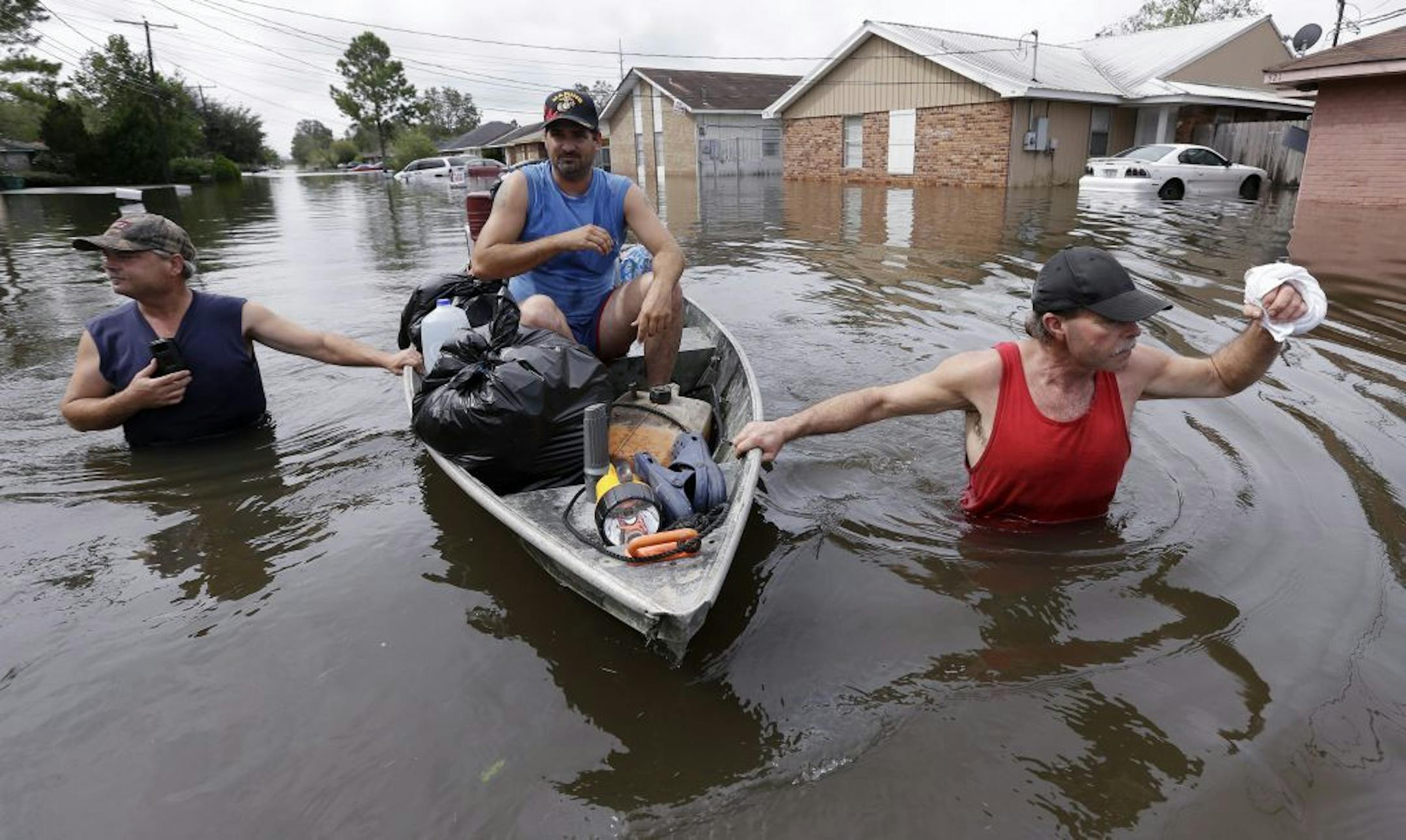 Christopher Tabb, left, with the help of Anthony Tabb, center, and friend, Frank Story, right, uses a boat to recover items from his flooded home, Friday, Aug. 31, 2012, in Reserve, La. Isaac crawled into the central U.S. on Friday, leaving behind a soggy mess in Louisiana. It will be a few days before the water recedes and people in flooded areas can return home. New Orleans itself was spared, thanks in large part to a levee system fortified after Katrina devastated the Gulf Coast in 2005.