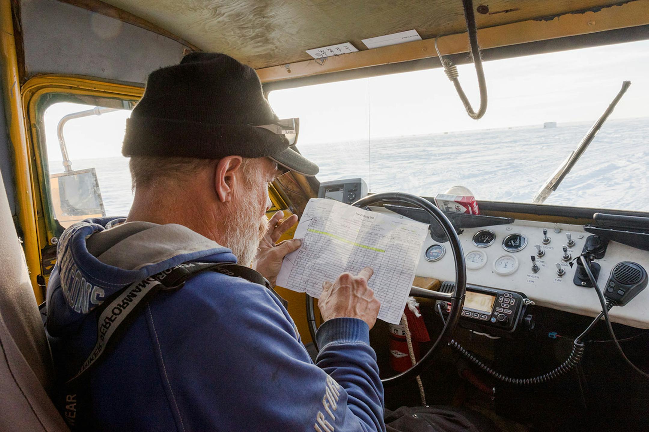 Ice guide Joe Anderson checks a roster that lists everything the guides need to know about who is on the ice: what houses customers are located in, which guide is responsible for them and which houses need to be moved. Photo By: Matt Weber