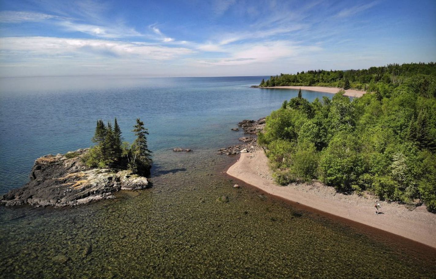 Day-18 - The 1.6 mile Cakewalk north of Grand Marais is the only section of trail that runs along the shore of Lake Superior outside of the Duluth Lake Walk. Here, Melanie McManus hikes the rocky shore of Lake Superior past the Tombolo Island.