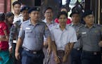 Two Reuters journalists Kyaw Soe Oo, center front, and Wa Lone, center back, are escorted by polices upon arrival at their trial Monday, Aug. 20, 2018