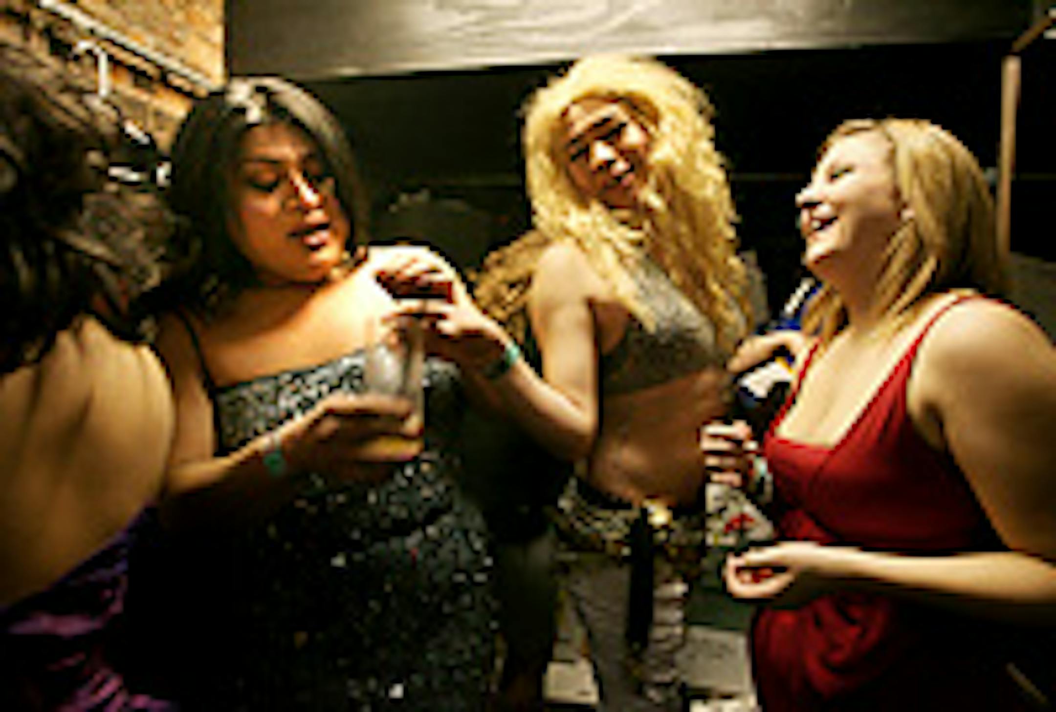 "Mistica, " left, from Mexico, "Shakira," center, from Venezuela, and Kaelyn Terhune, right, from Minneapolis, toasted their dresses with a drink at The Saloon during "Fiesta Latino."