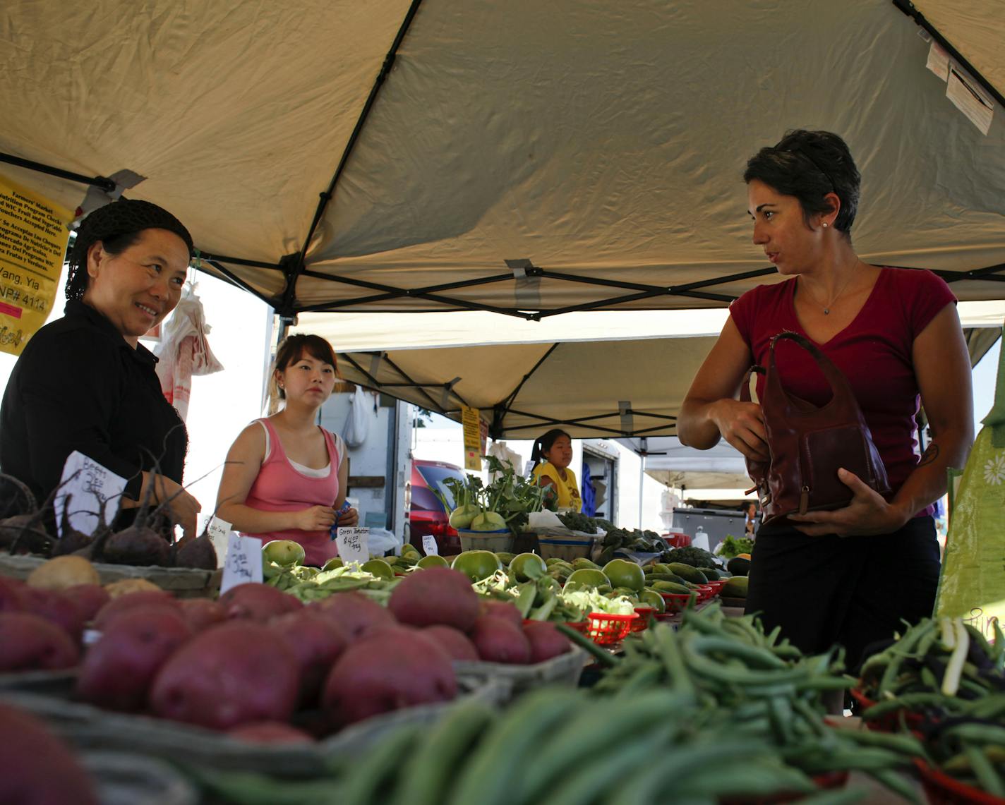 Chue Hang, left, answers a question of Suneeta Kaasan as she shops at the Midtown Farmer's Market with her mother Peggy Asrani in Minneapolis, Minn. Saturday, June 29, 2012. ] MEGAN TAN/ STAR TRIBUNE&#x201a;&#xc4;&#xa2;megan.tan@startribune.com. ORG XMIT: MIN2013090420190547